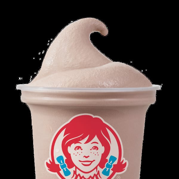 A Wendy's Frosty, a light brown frozen dessert, in a clear plastic cup with the Wendy's logo.