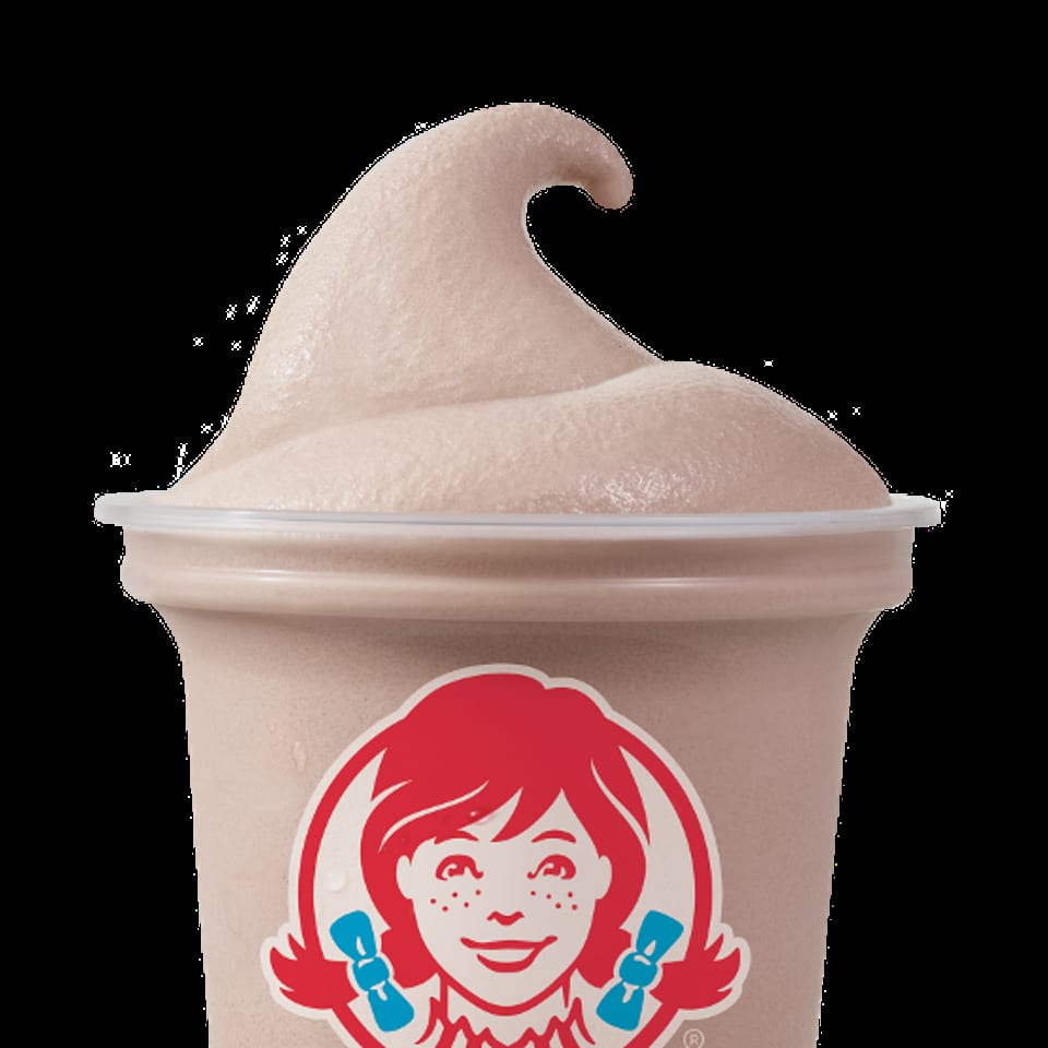 A Wendy's Frosty, a light brown frozen dessert, in a clear plastic cup with the Wendy's logo.